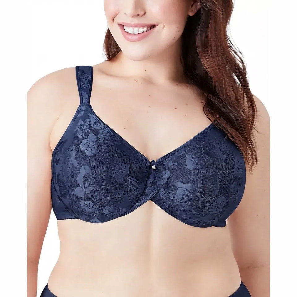 A woman wearing a navy blue floral lace bralette with a small gold button closure at the center front, shown against a plain white background.