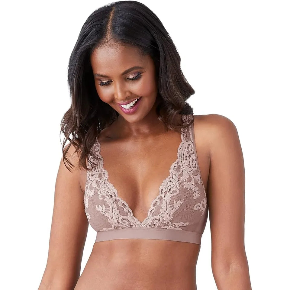 A woman wearing a beige lace-trimmed bralette against a plain white background.