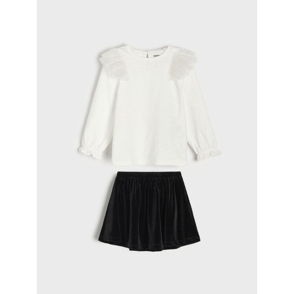 A two-piece girls' outfit set featuring a white long-sleeve top with ruffled shoulder details and a black pleated skirt, displayed flat on a light gray background.