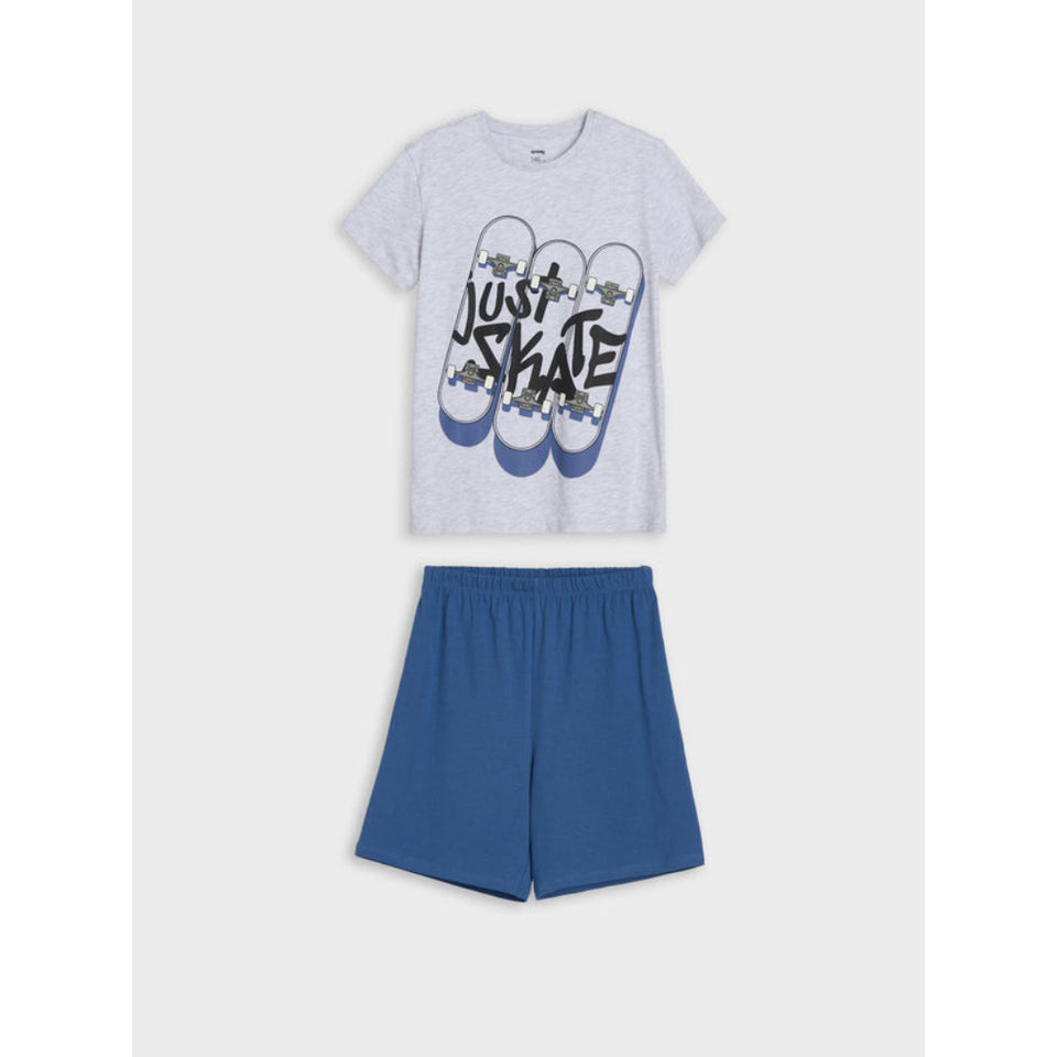 A two-piece kids' lounge set consisting of a light gray heather t-shirt with a graphic print of flip-flops and the words 'JUST SKATE' in black, paired with solid blue shorts, displayed on a light gray background.