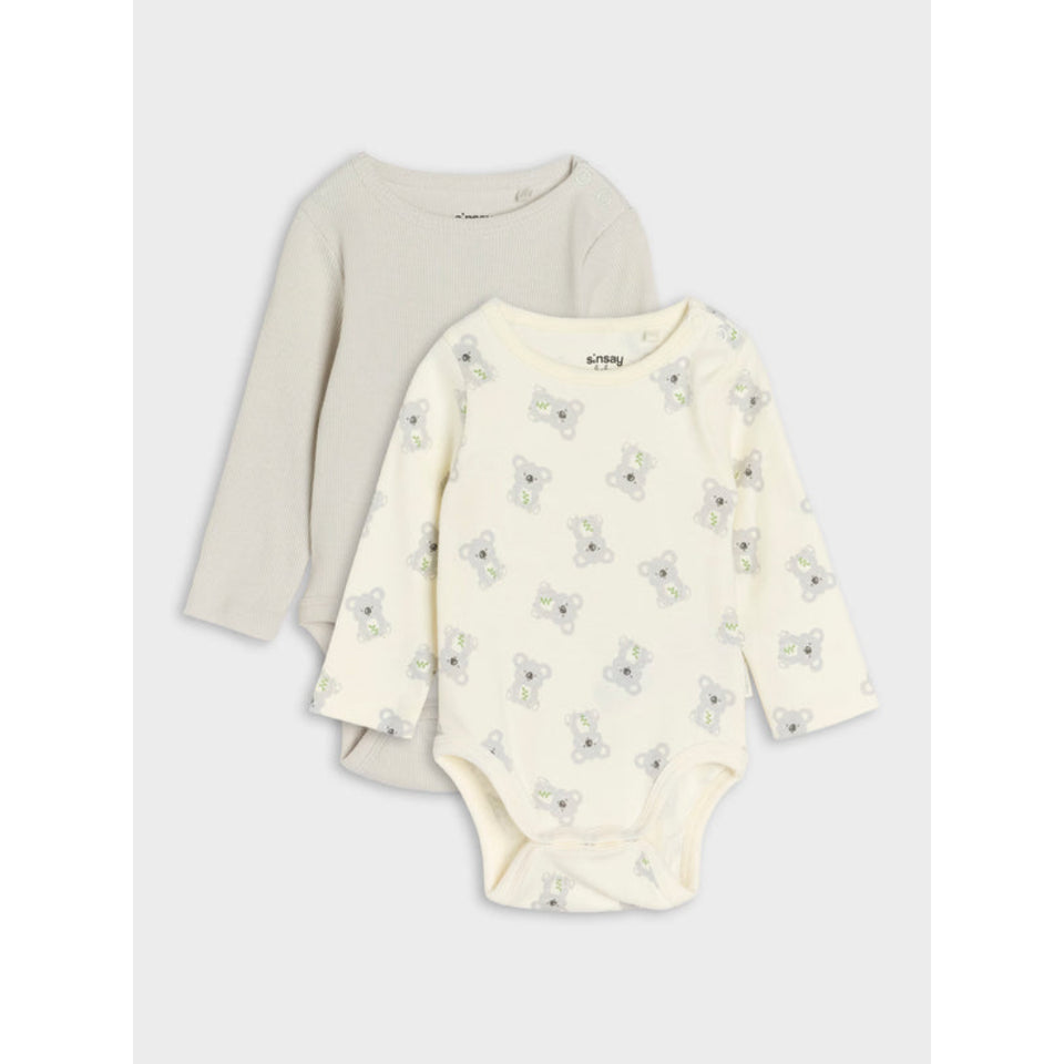 Two long-sleeve baby bodysuits stacked on a light gray background. The front bodysuit is cream with a repeating light blue bunny print, and the back bodysuit is a solid light beige/taupe color.
