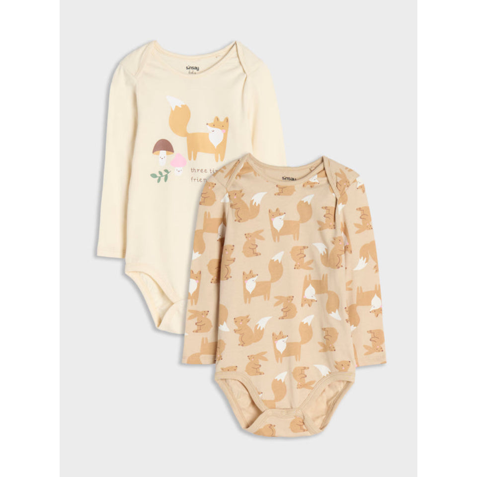 Two long-sleeve baby bodysuits in warm cream and tan shades, featuring woodland animal prints. The top bodysuit is cream with a fox and mushroom graphic, while the bottom bodysuit is tan with an all-over fox pattern.