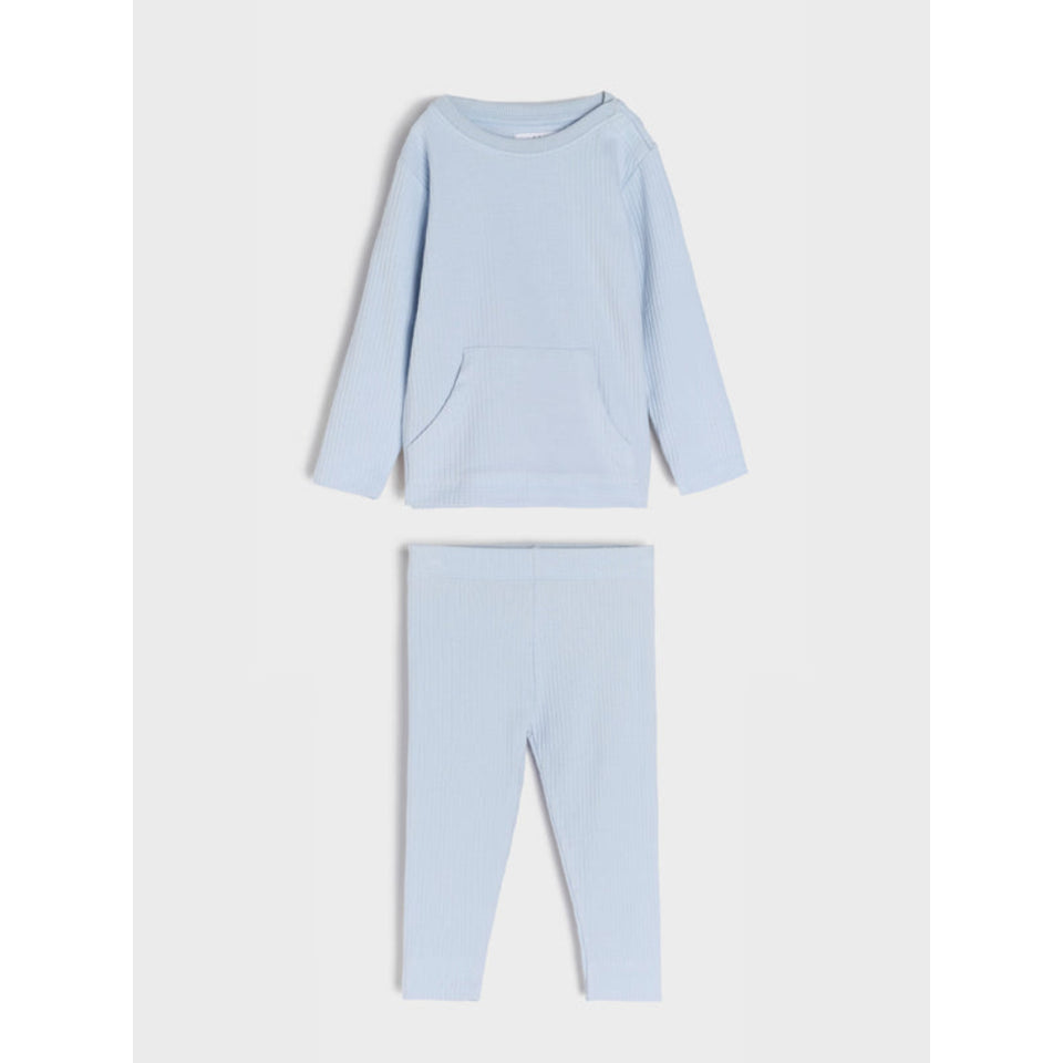 A two-piece children's loungewear set in light blue, featuring a long-sleeve top with a front kangaroo pocket and matching leggings, laid flat on a light gray background.