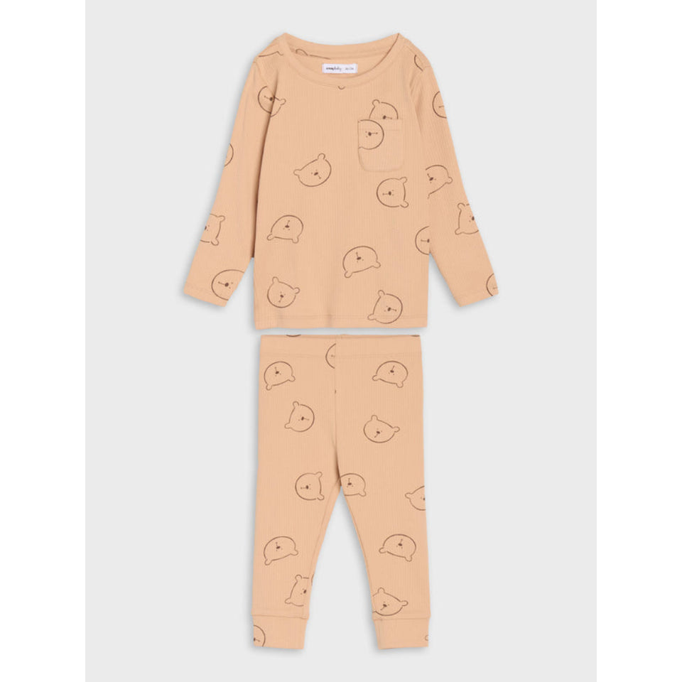 A two-piece children's pajama set in a warm peach-beige color, featuring a long-sleeve top with a small chest pocket and matching pants, both printed with a simple line-art pattern of cartoon faces.