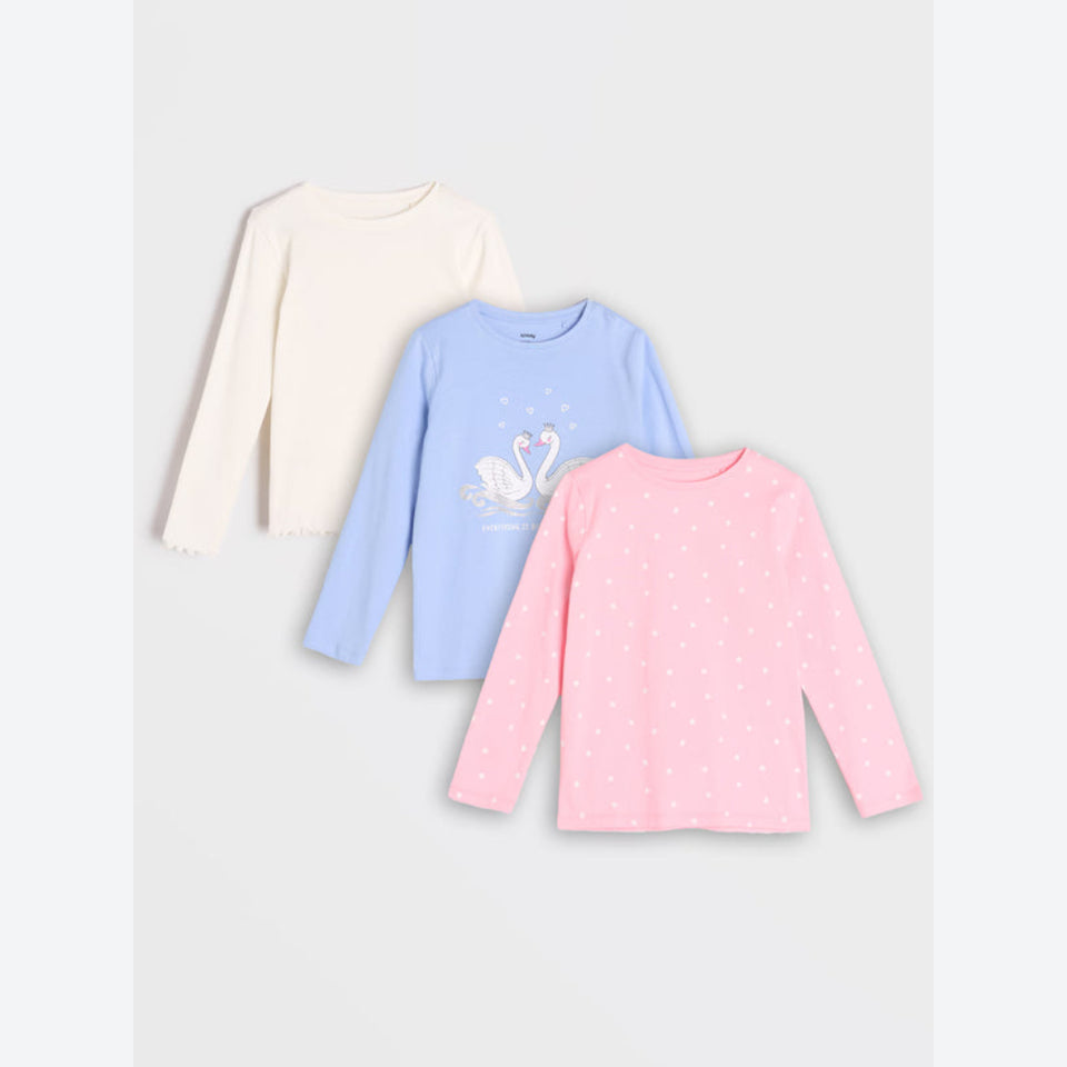 Three long-sleeve children's tops arranged in a fan layout on a light gray background: an off-white top with scalloped edges, a light blue top with a swan graphic, and a pink top with small white polka dots.