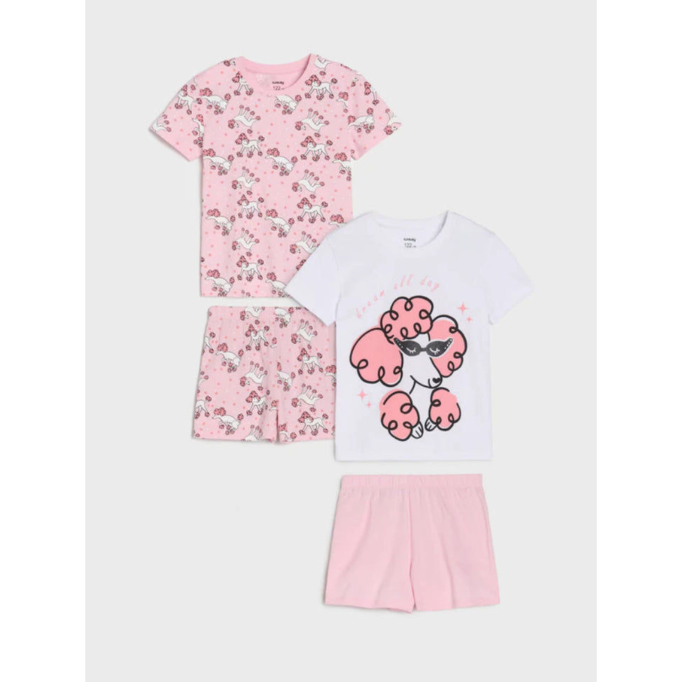 A children's pajama set laid out on a light gray background, featuring a pink short-sleeve pajama top and matching shorts with a cherry print, a white short-sleeve pajama top with a pink poodle graphic, and solid light pink shorts.