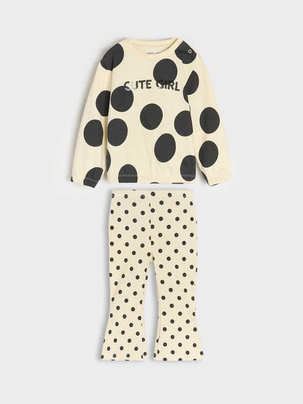 A two-piece children's pajama set from the brand 'Elite Girl' featuring a cream-colored long-sleeve top and matching flared pants, both decorated with black polka dots.