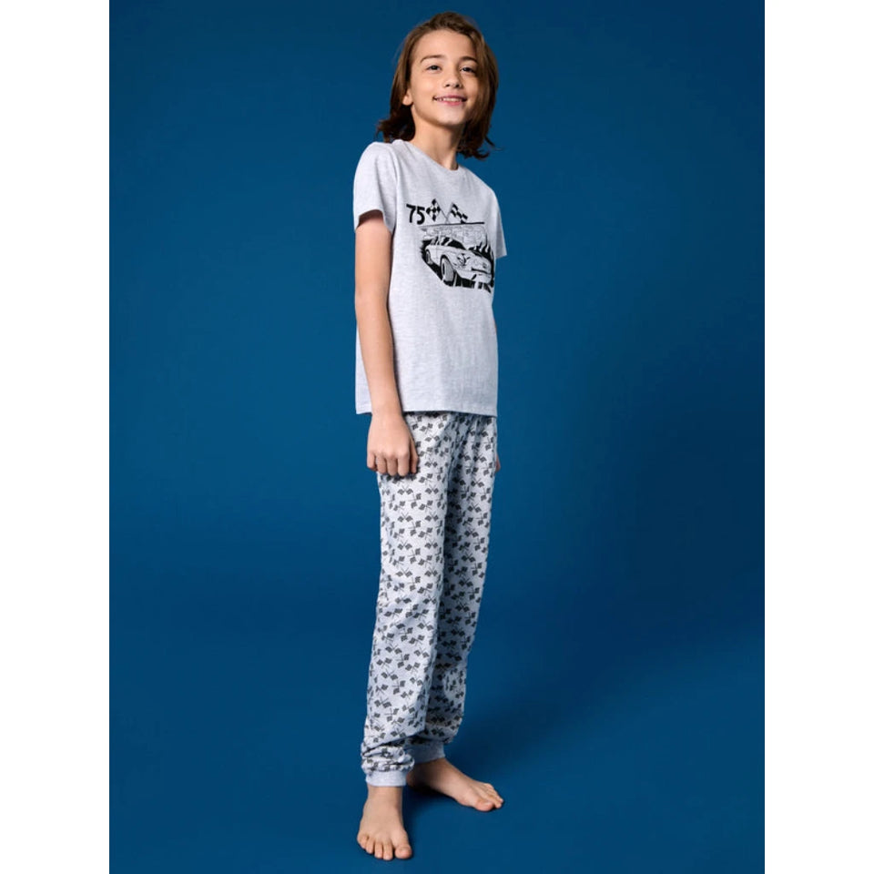 A child model wearing a light gray short-sleeve t-shirt with a black graphic print and matching gray patterned pajama pants, standing against a solid blue studio background.