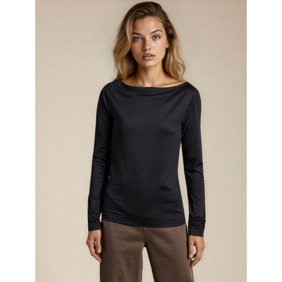 A woman modeling a black long-sleeve boat-neck top against a plain beige studio background.