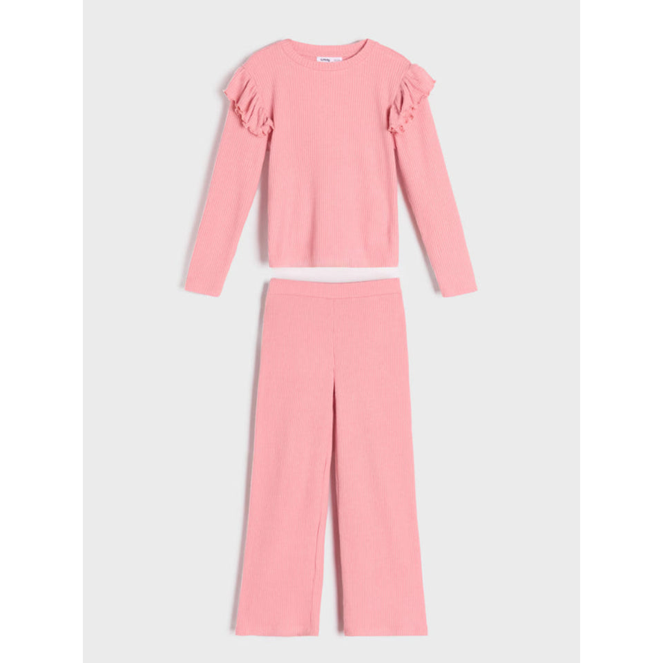 A two-piece girls' knit set in a soft pink color, featuring a long-sleeve crop top with ruffle details on the shoulders and matching wide-leg pants, displayed against a light gray background.
