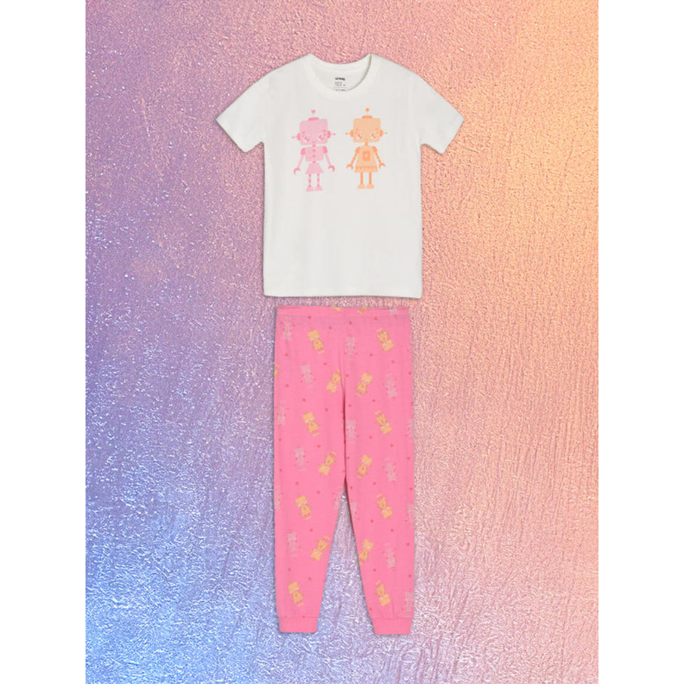 A children's two-piece pajama set consisting of a white short-sleeve top with pink and orange cartoon girl graphics, and pink pants with a small yellow pattern, displayed flat against a textured pink, purple, and blue gradient background.