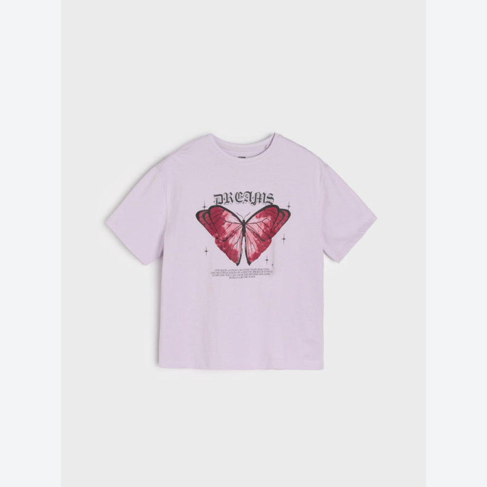 A light lavender short-sleeve t-shirt with a graphic print of a pink butterfly and the word 'DREAMS' in a gothic font on the front, displayed against a light gray background.