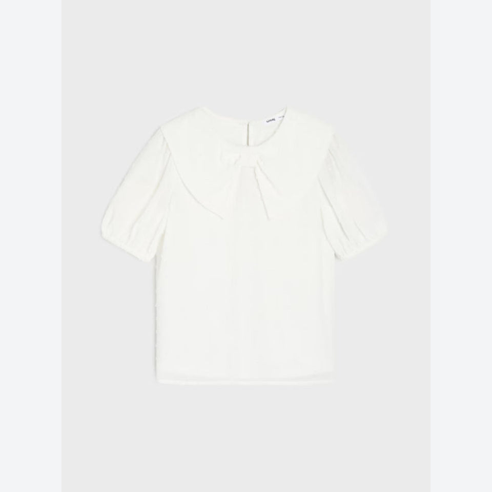 An off-white short-sleeve blouse with a large ruffled collar and a bow detail at the neckline, displayed flat against a light gray background.