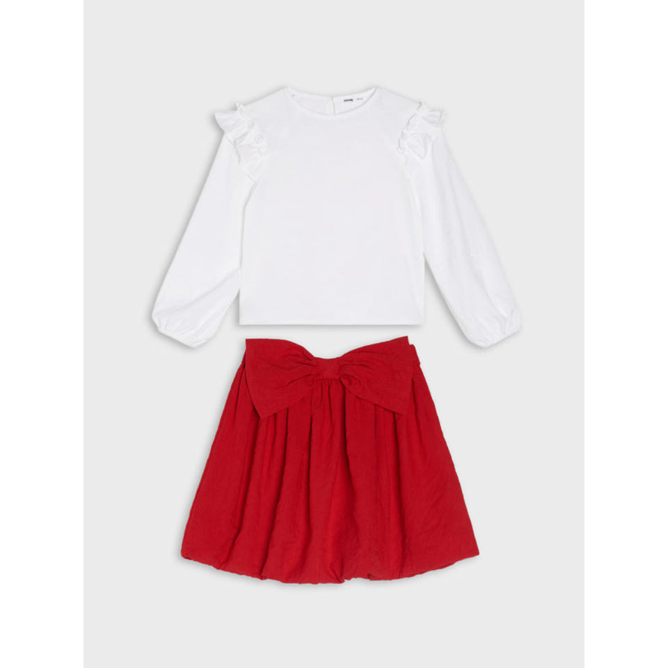 A two-piece girls' outfit set featuring a white long-sleeve crop top with ruffle details on the shoulders and a red pleated skirt with a large bow at the waist, displayed flat on a light gray background.