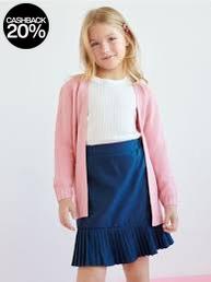 Young girl wearing a pink cardigan, white top, and blue skirt on a white background
