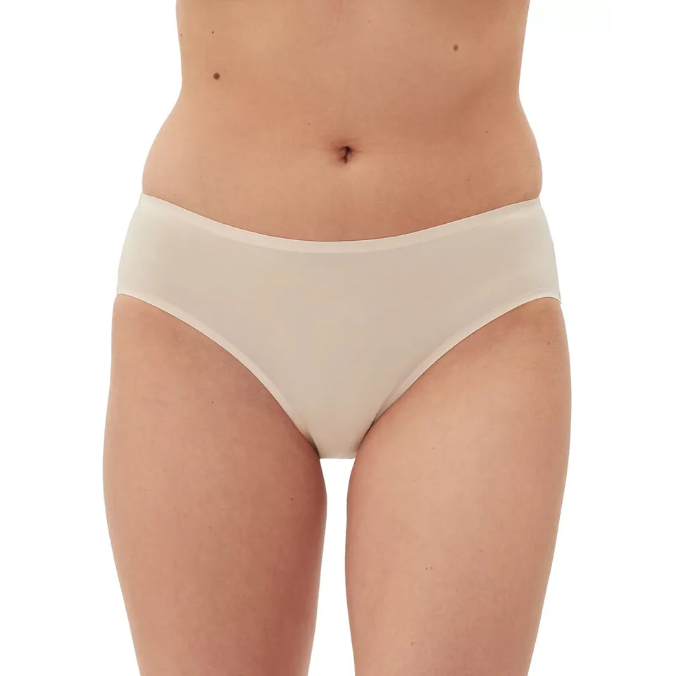 A close-up of a model's lower torso wearing a pair of seamless, light beige high-waisted briefs against a plain white background.