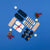 A flat-lay arrangement of assorted socks on a solid blue background, styled with decorative props including white stars, pinecones, and red berries. The socks include solid navy, striped navy and white, white with a red bow and cartoon face, and navy with a brown animal print.