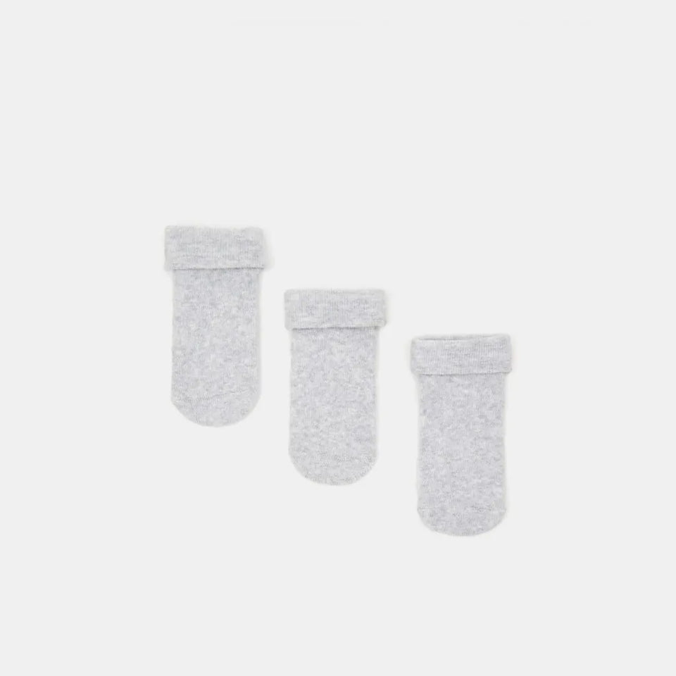 Three light gray knit baby socks with ribbed cuffs, arranged diagonally on a solid light gray background.