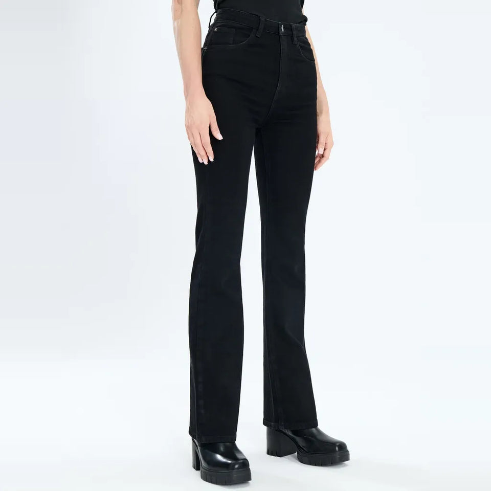 A model wearing black high-waisted straight-leg jeans with a subtle sheen, paired with black platform shoes, shown from the waist down on a white studio background.