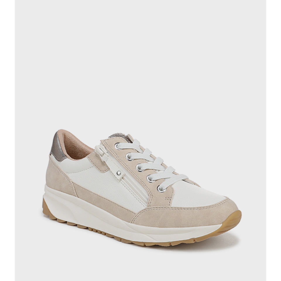 A low-top sneaker in white and beige suede, featuring a side zipper, white laces, and a chunky white midsole with a tan outsole, shown against a light gray background.