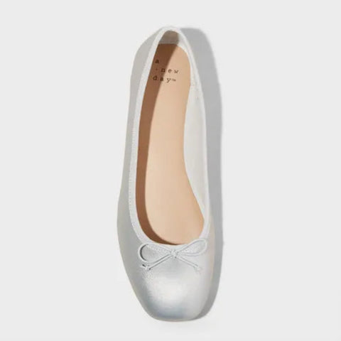 Silver flat shoe with a bow on a white background
