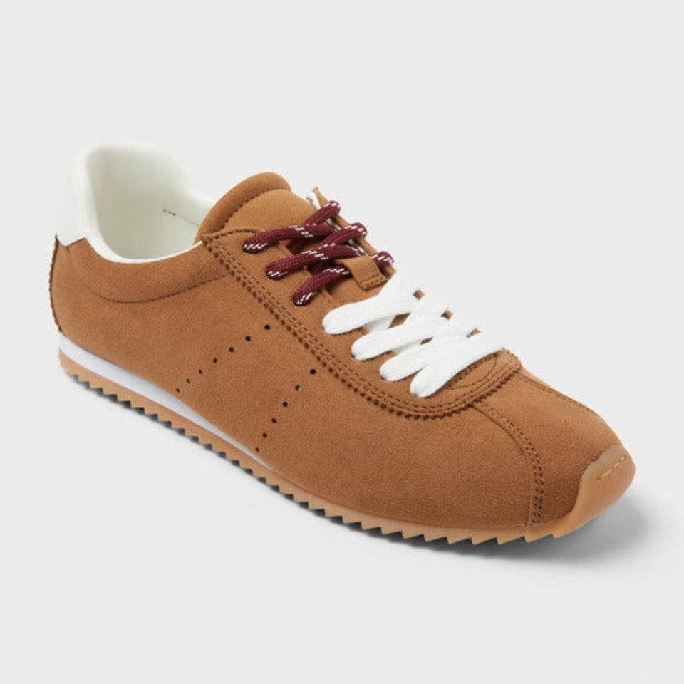 Brown sneaker with white laces on a light gray background