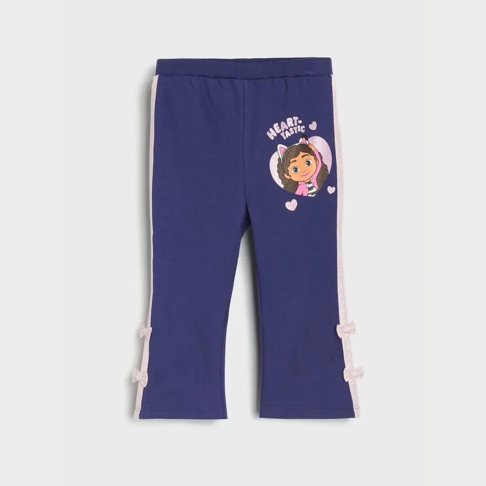 A pair of navy blue cropped pants for kids, featuring a Dora the Explorer graphic on the left thigh and light pink side stripes with bow details at the cuffs, shown against a light gray background.