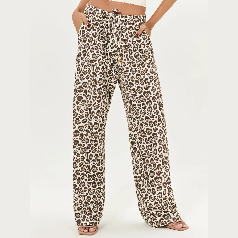 A pair of wide-leg pants with a brown and beige leopard print pattern, modeled from the waist down on a plain white background.