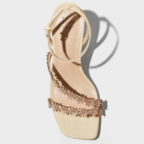 Beige sandal with floral embellishments on a light gray background