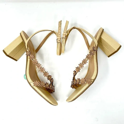 Gold high-heeled shoes with floral designs on a white background