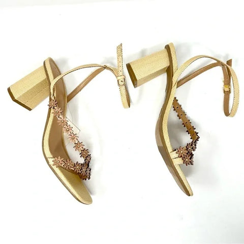 Gold high-heeled shoes with floral embellishments on a white background