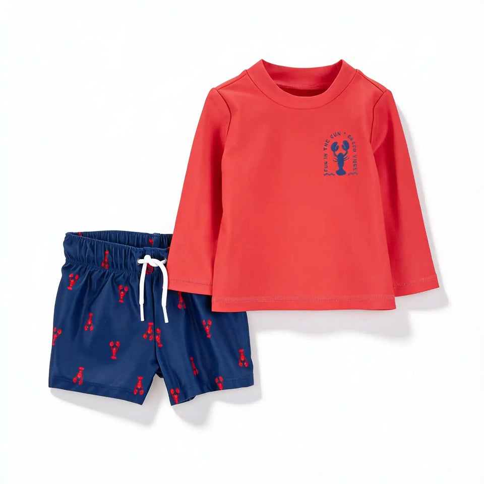 A children's two-piece swimwear set featuring a coral red long-sleeve rash guard with a blue lobster graphic on the chest, paired with navy blue swim shorts printed with red lobster motifs and a white drawstring.
