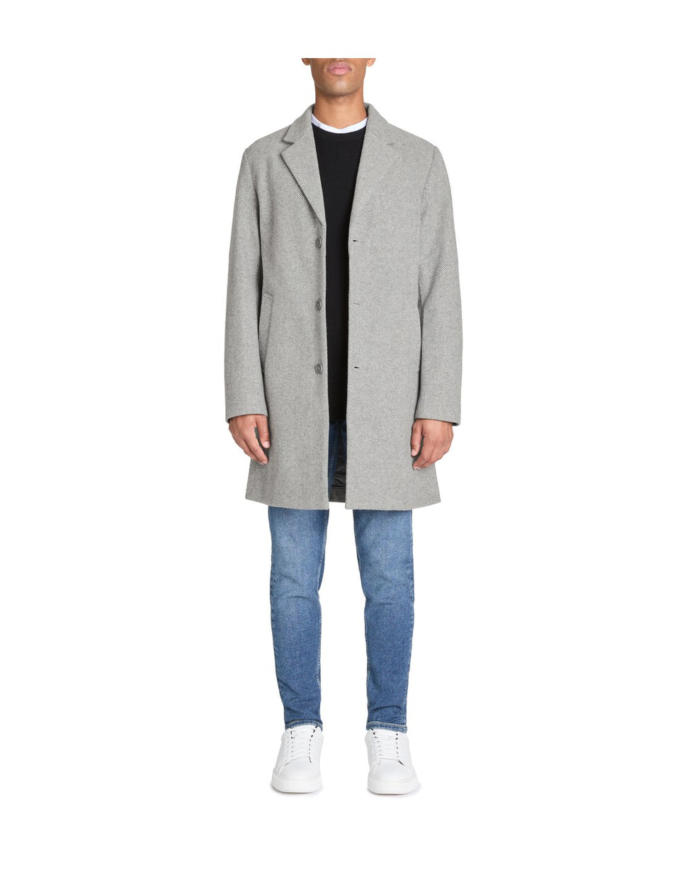 Person wearing a gray coat, black shirt, and blue jeans on a white background