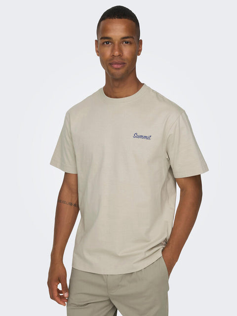 Man wearing a beige t-shirt with a logo on a light gray background