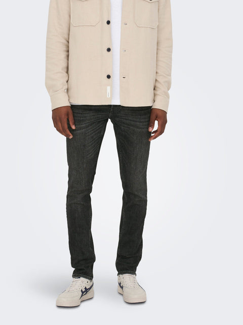 Person wearing a beige jacket, dark jeans, and white sneakers on a white background
