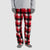 A person wearing red, black, and white buffalo plaid fleece pants with a gray long-sleeve top and gray socks, shown from the chest down on a light gray background.