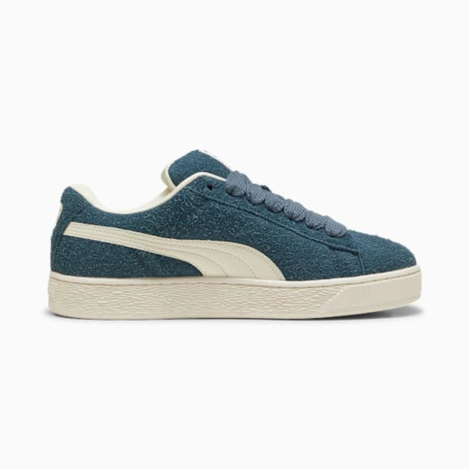 A dark green suede sneaker with a white side stripe, white laces, and a textured white sole, shown from a side profile view on a light gray background.