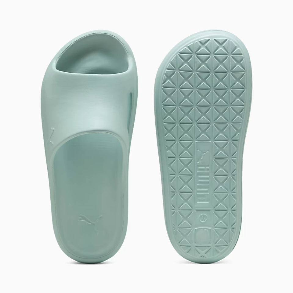 A pair of Puma slide sandals in a light mint green color, shown from both the top and bottom views against a clean white background.