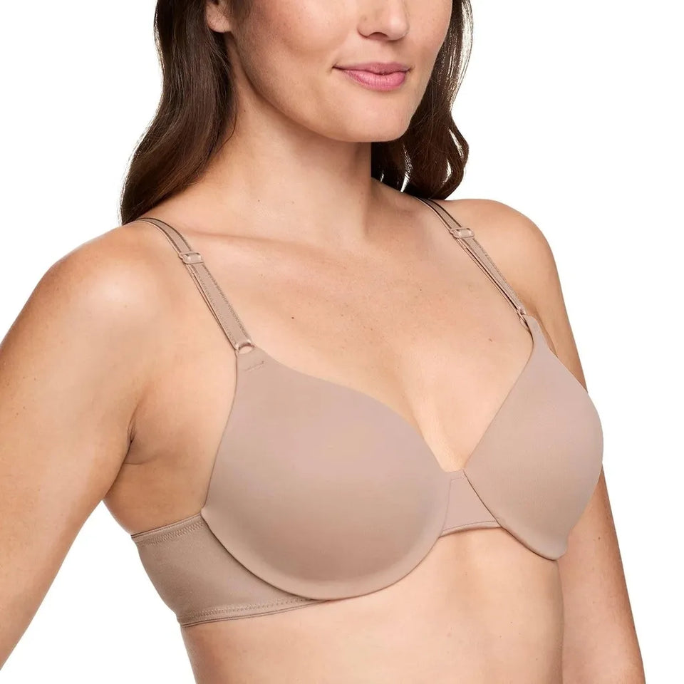A woman wearing a seamless, wireless bra in a light taupe-beige color, shown from the chest up against a plain white background.