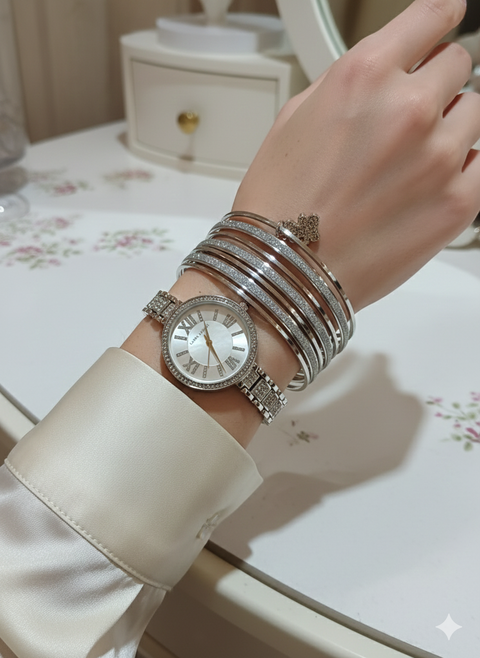 Hand wearing a silver watch and bracelets on a floral-patterned surface