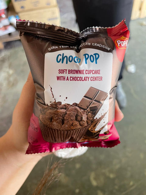 Choc Pop soft brownie cupcake packaging held by a hand on a blurred background
