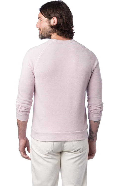 Man wearing a light pink sweater and white pants on a white background