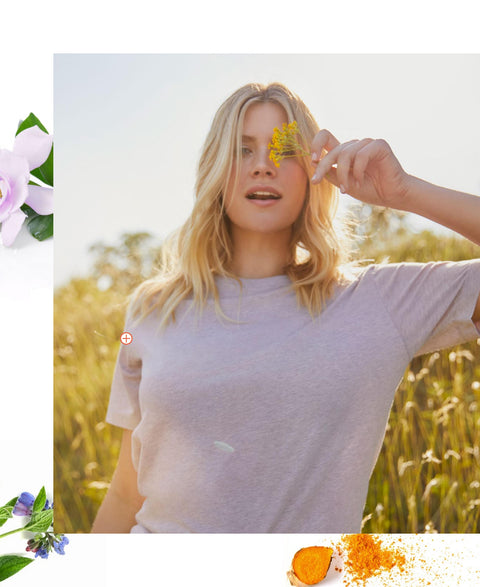 Woman holding a flower to her face with a blurred background of a field