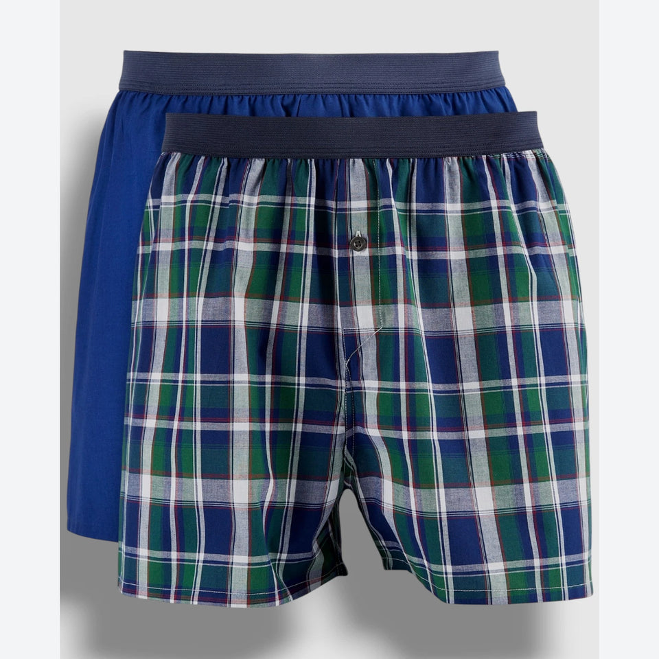 Two pairs of men's boxer briefs displayed together against a light gray background. The front pair features a blue, green, and white plaid pattern with a dark navy waistband, and the pair behind it is a solid royal blue with a matching dark navy waistband.