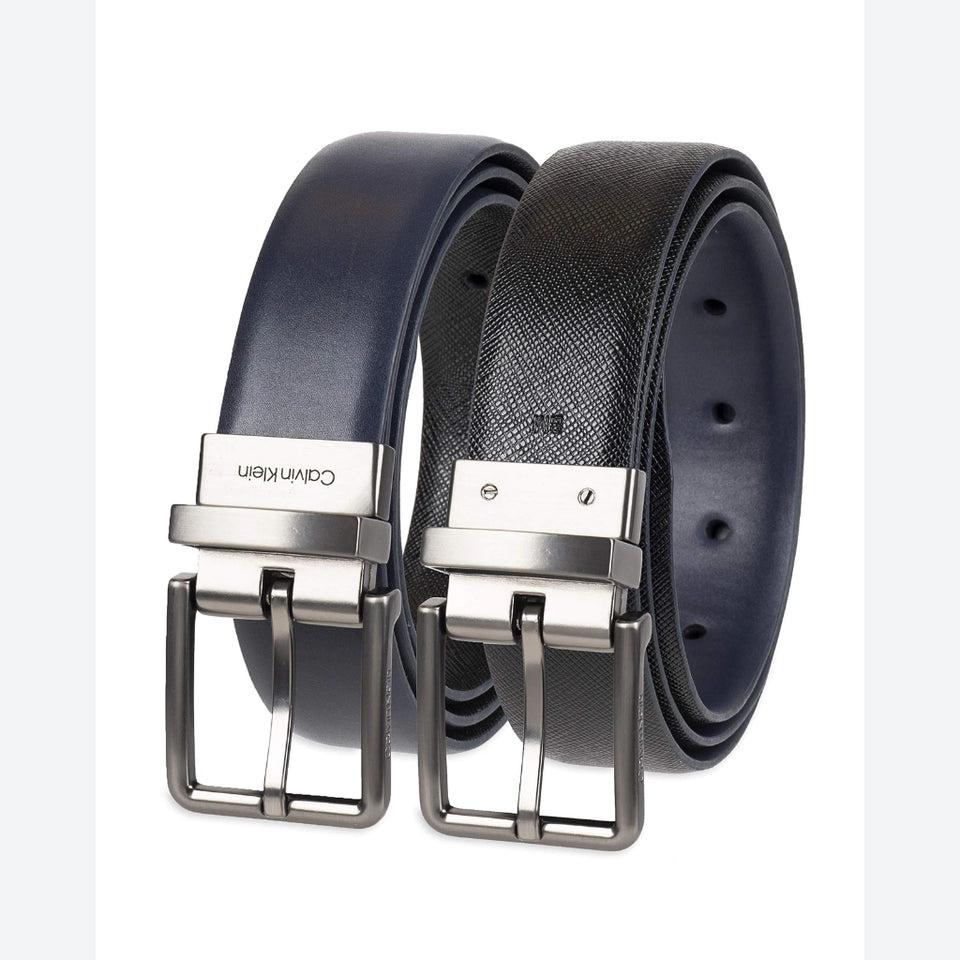 Two Calvin Klein men's belts, one navy blue smooth leather and one black textured leather, both with silver-tone buckles, displayed on a white background.