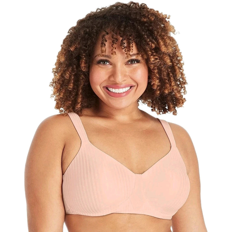 A smiling woman with curly brown hair wearing a light peach ribbed bralette against a plain white background.