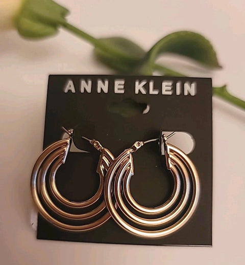 Gold hoop earrings on a Anne Klein branded card with green leaves in the background