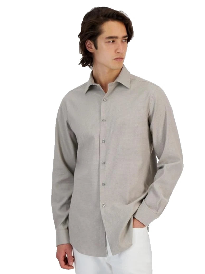 A man wearing a light gray long-sleeve button-down shirt and white pants, standing against a plain white background.