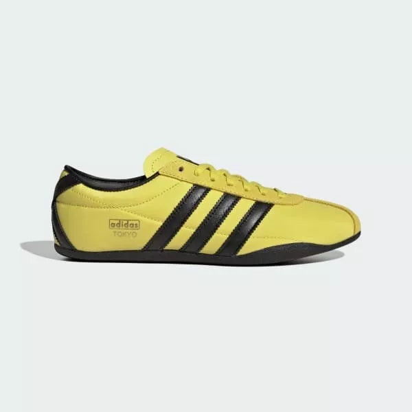 Yellow Adidas sneaker with black stripes on a white background