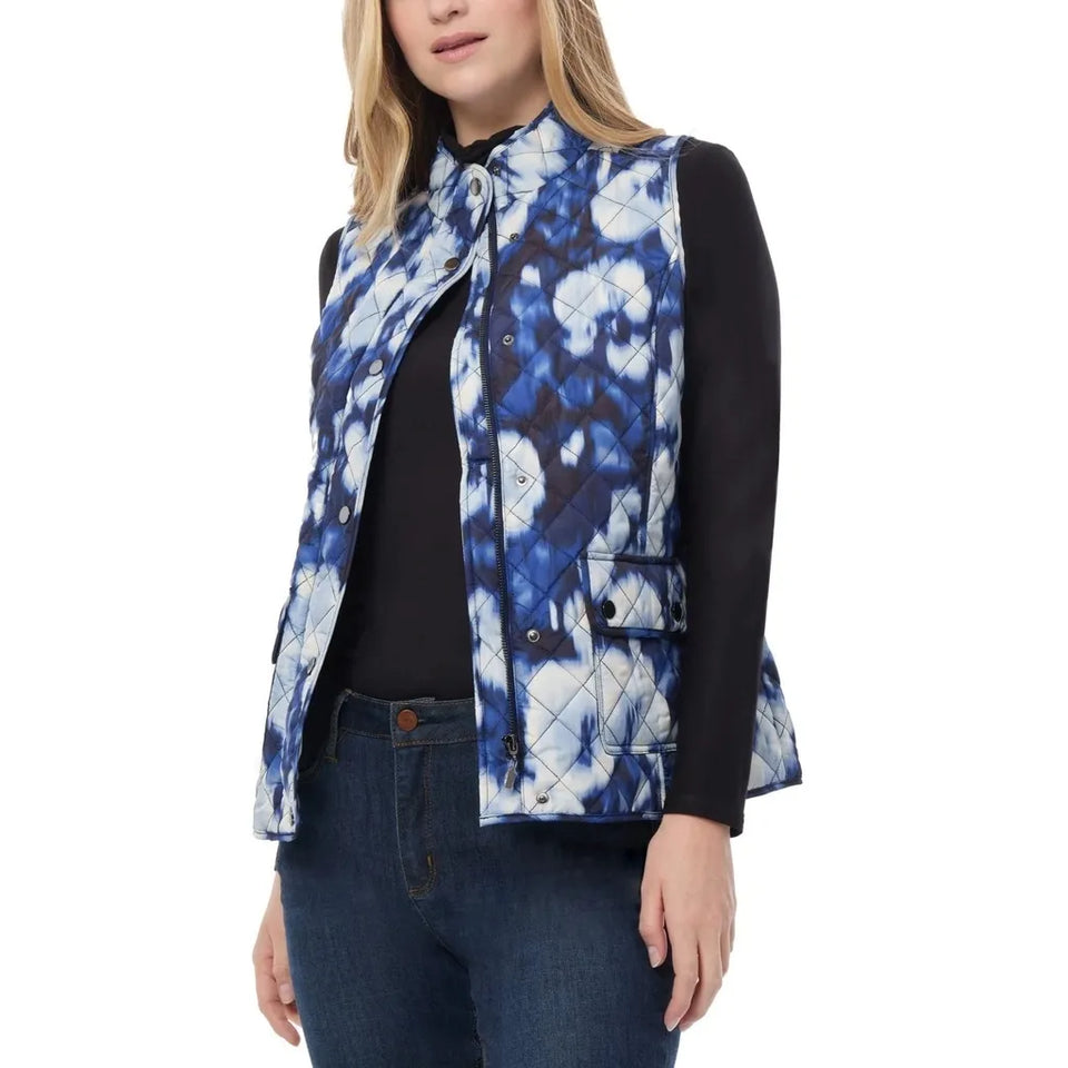 A woman wearing a sleeveless quilted vest with a blue and white floral tie-dye pattern over a black long-sleeve top and dark blue jeans, photographed against a plain white background.